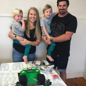 A family standing behind a green monster truck cake.