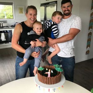 A family standing behind a birthday cake decorated to look like a swimming pool.