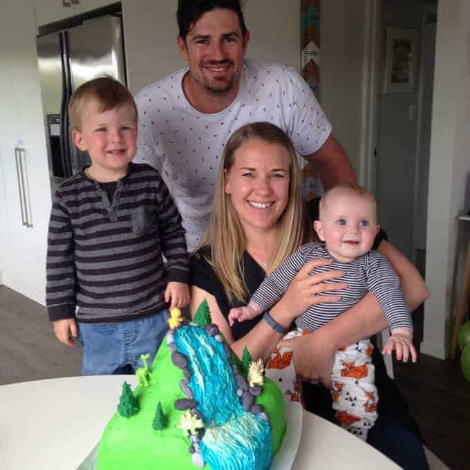 A family sitting around a dinosaur birthday cake.