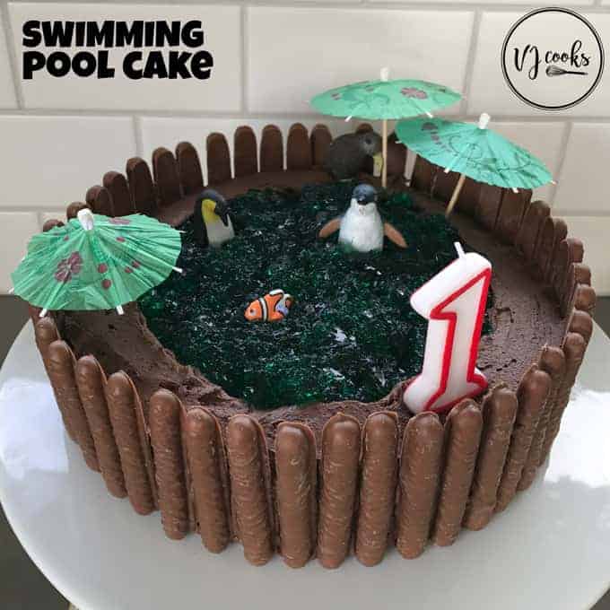 A chocolate birthday cake decorated to look like a swimming pool sitting on a white plate.