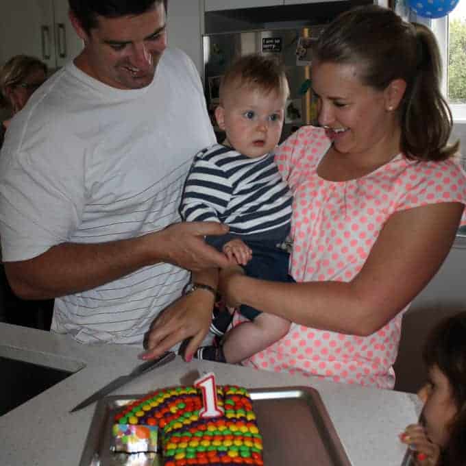 A family standing behind a decorated number one cake.