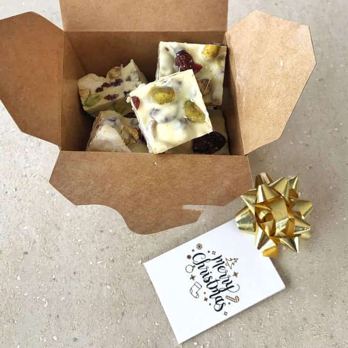 White christmas rocky road in a brown gift box on a grey bench.
