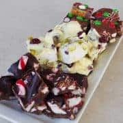 Xmas rocky road three ways sitting on a white platter on a grey bench.