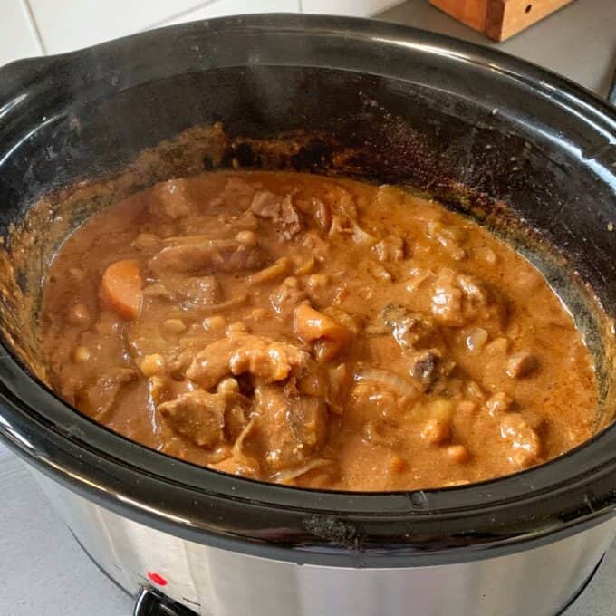 A slow cooker Moroccan lamb stew filled with chunky pieces of lamb, carrots, peas, and a thick brown gravy.