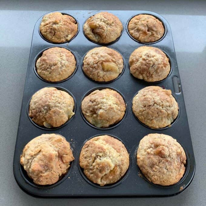 Easy Oaty Muffins A muffin tray containing twelve freshly baked oaty muffins sits on a countertop.