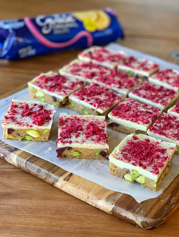 Sliced pieces of Cranberry and pistachio slice on a wooden chopping board.