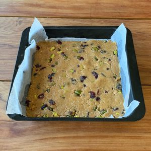 The base of Cranberry and pistachio slice pressed into a lined baking tin.