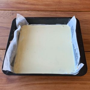 A mix of butter and sweetened condensed milk in a lined baking tin.