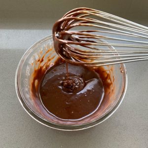 Nutella ganache being whisked in a glass bowl.