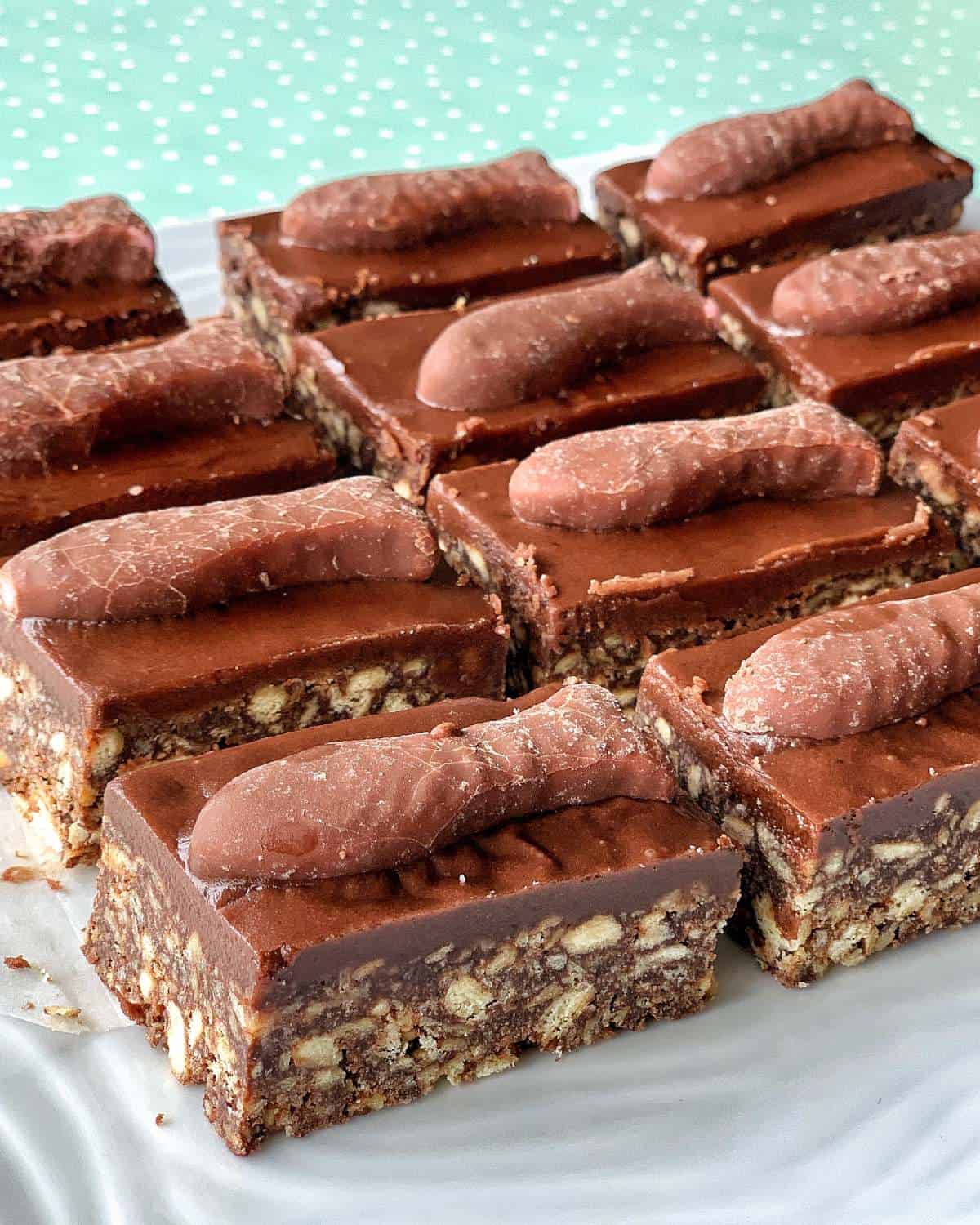 Chocolate fish slice biscuit slices topped with chocolate-coated finger-shaped candies, arranged neatly on a white plate.