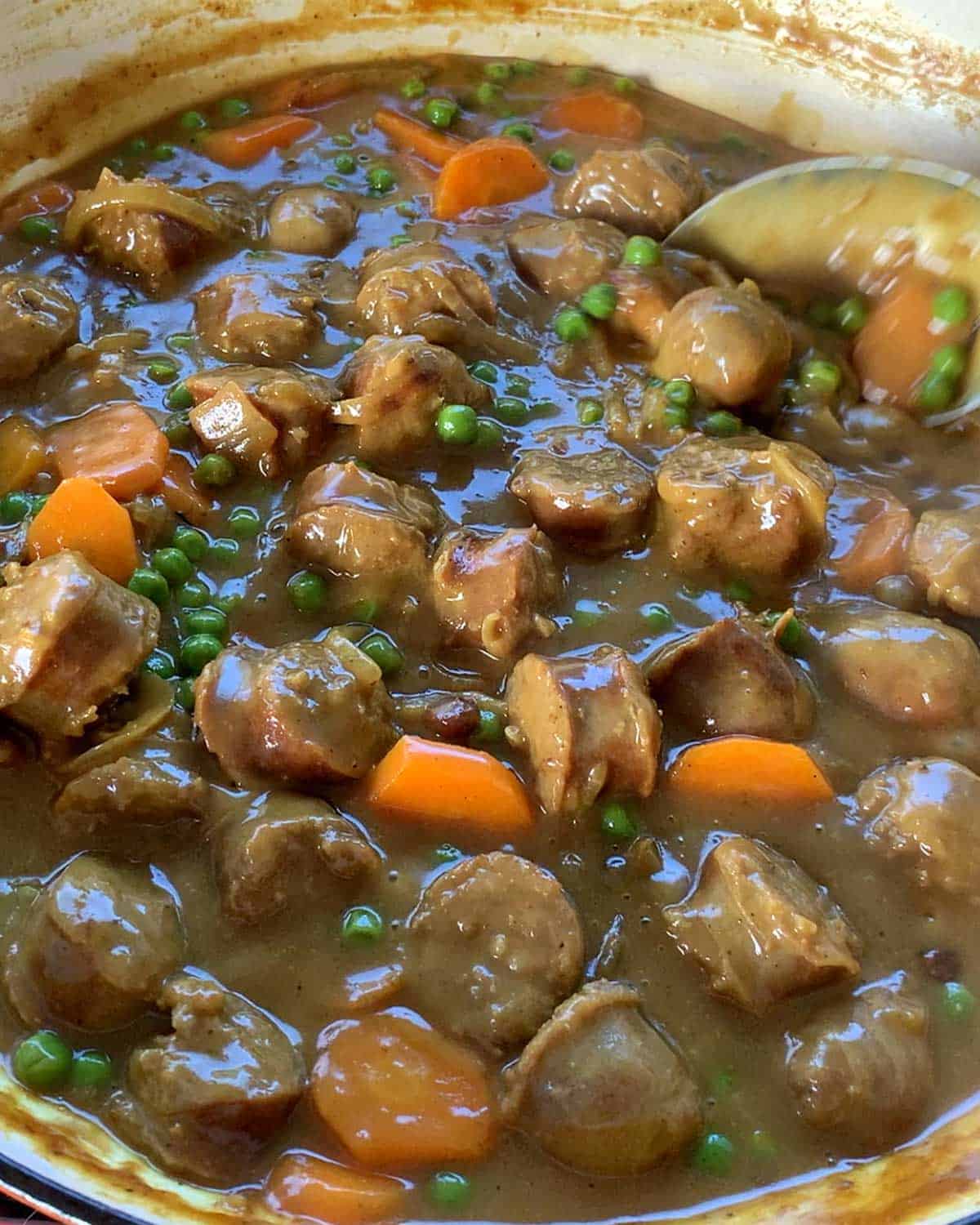 A close up of curried sausages in a casserole dish.