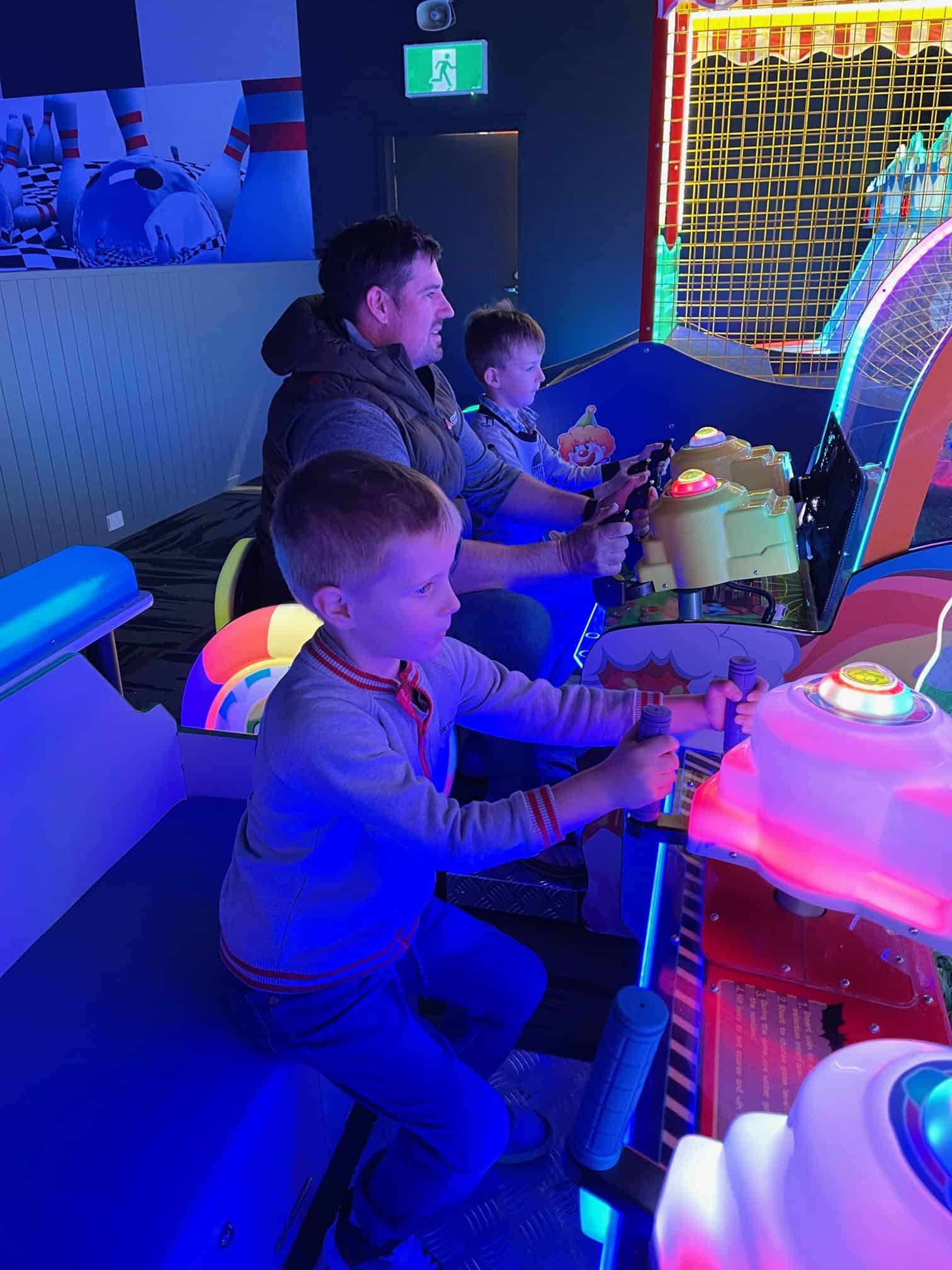 Father and sons playing arcade games.