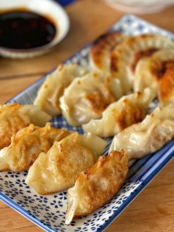 Pork and Ginger Dumplings on a blue plate with soy sauce