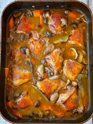 a large tray of chicken in a rich wine sauce