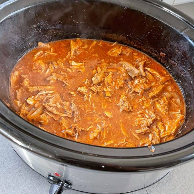 Slow Cooker Mexican Pulled Pork Slow Cooker Mexican Pulled Pork simmers in a rich red sauce inside a black slow cooker, filling your kitchen with mouthwatering aromas.