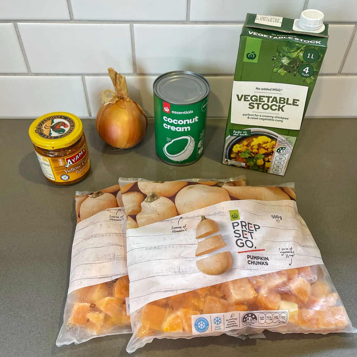 Ingredients for pumpkin soup on a grey bench.