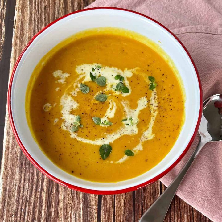 Pumpkin Soup in a white bowl on a wooden table.