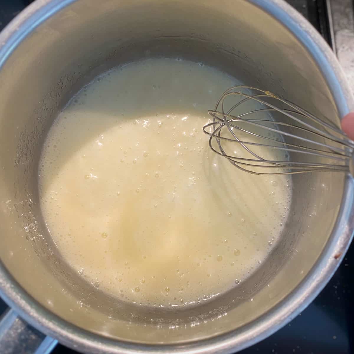 Cream and sugar in a pot with a whisk.