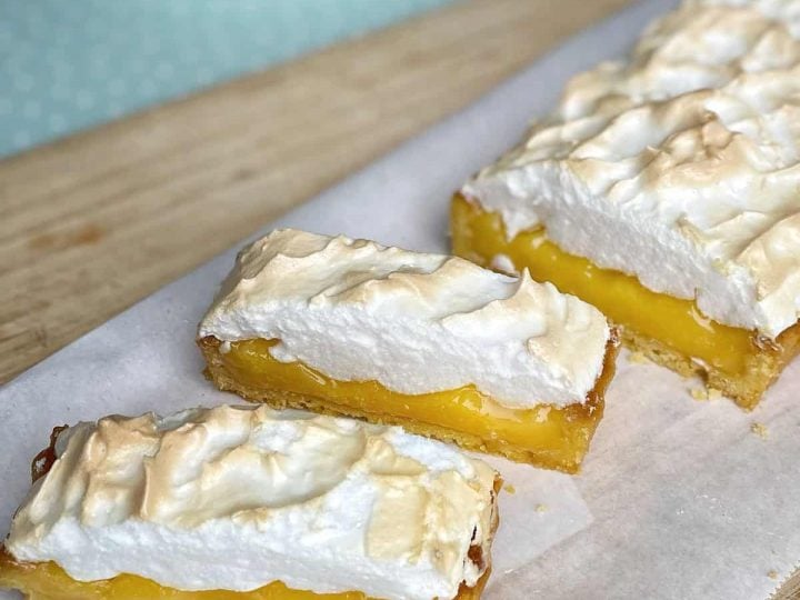 Sliced up Lemon Meringue Pie on a wooden chopping board.
