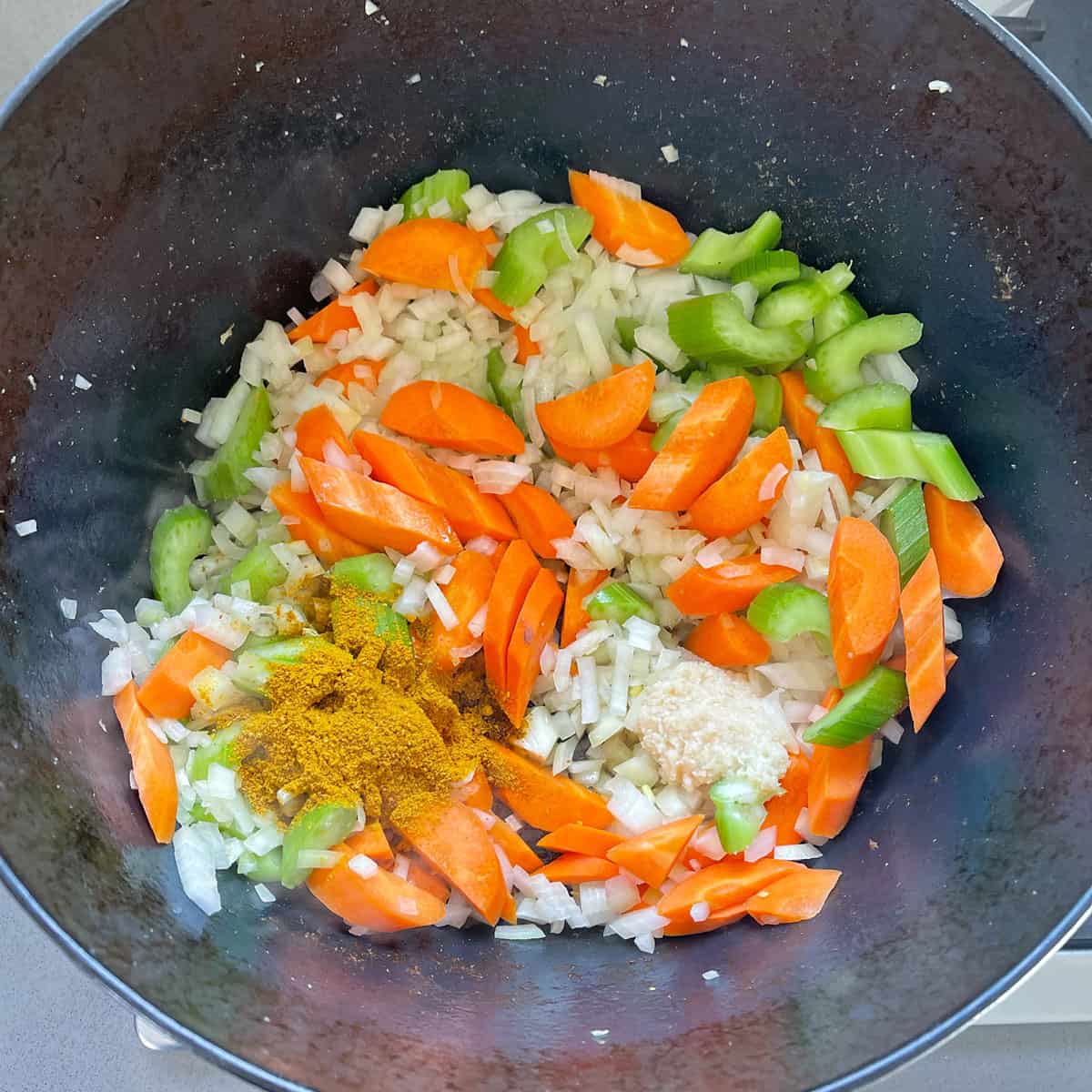 Vegetables cooking in a black pot.