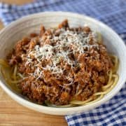 Spaghetti bolognese with parmesan in a white bowl.