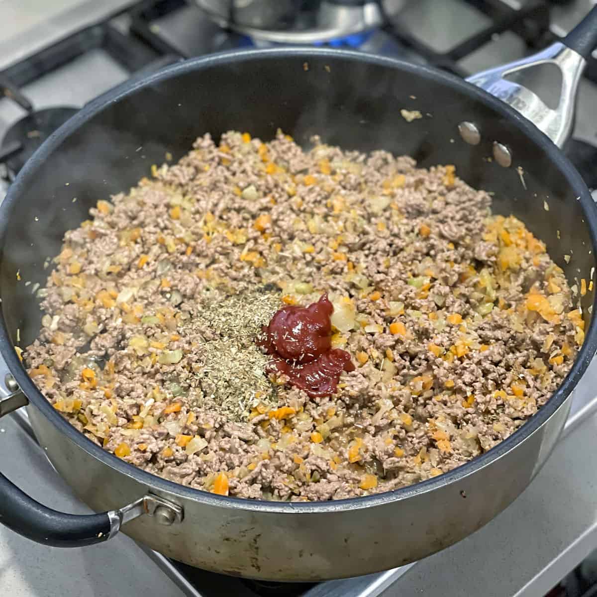 Mince, tomato paste and herbs cooking in a pan.