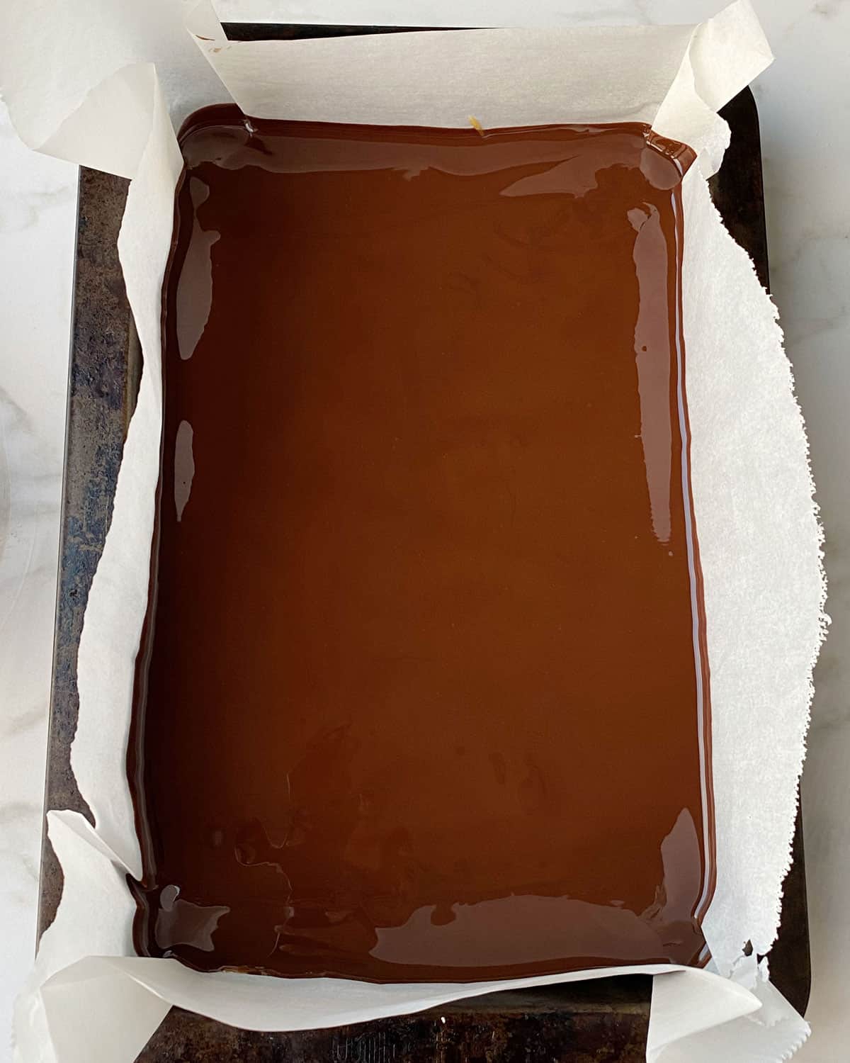 A lined baking filled with a slice covered in chocolate.