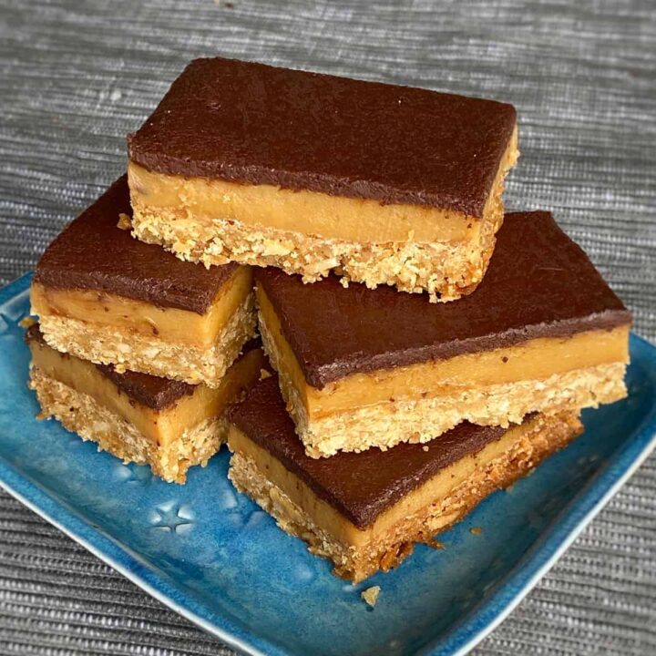 Caramel coconut slice sitting on a blue plate.