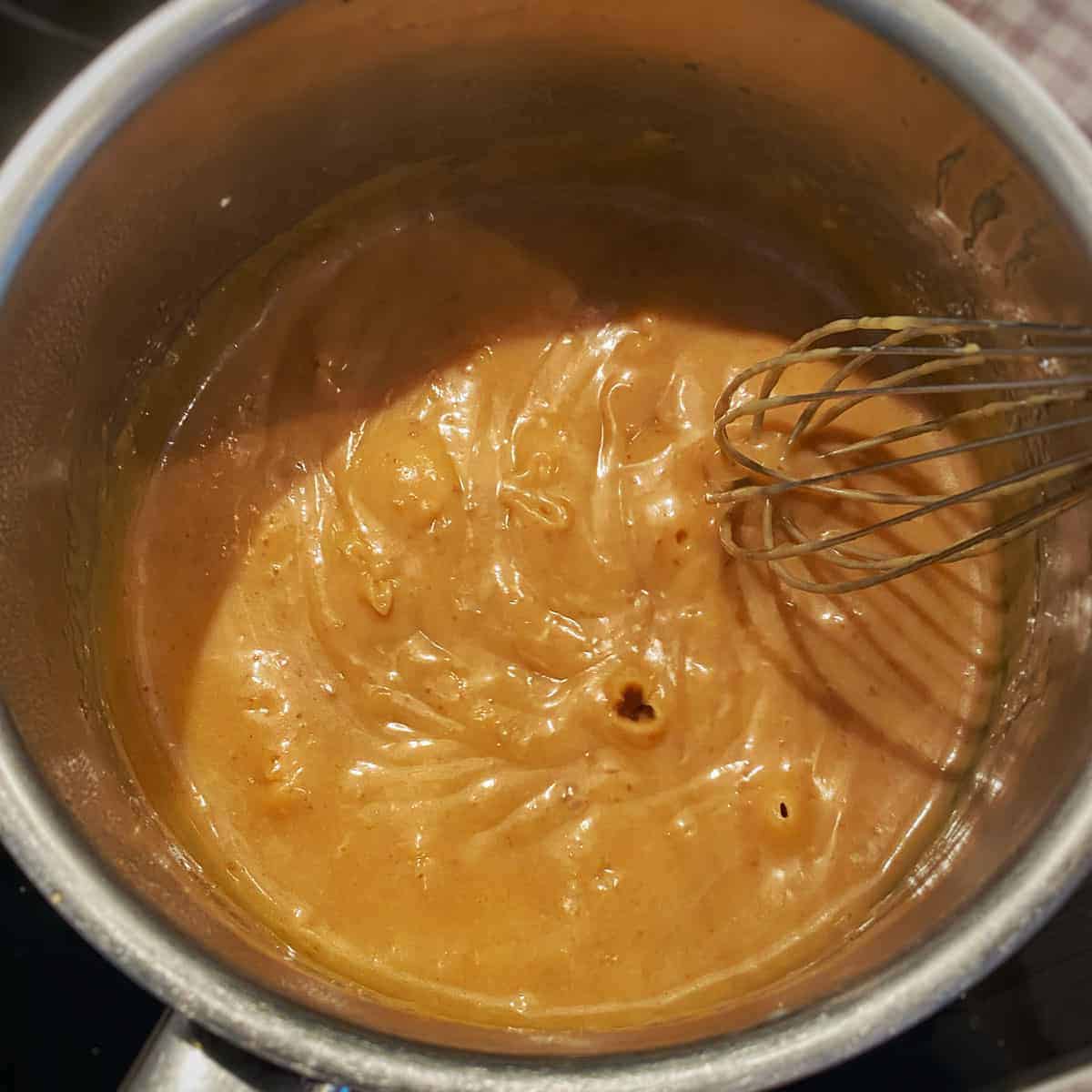 Caramel cooking in a saucepan being whisked.