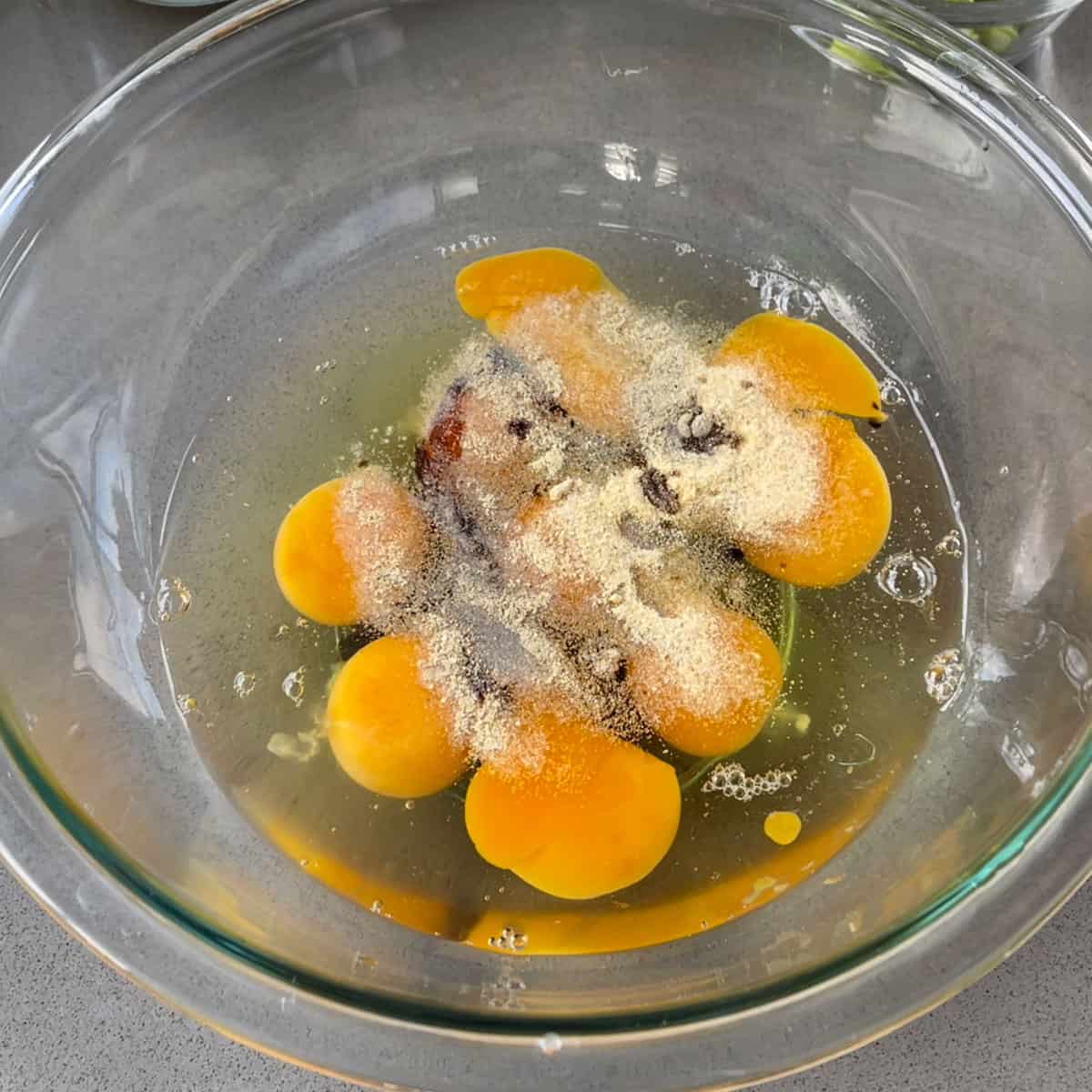 Raw eggs and spices in a glass bowl