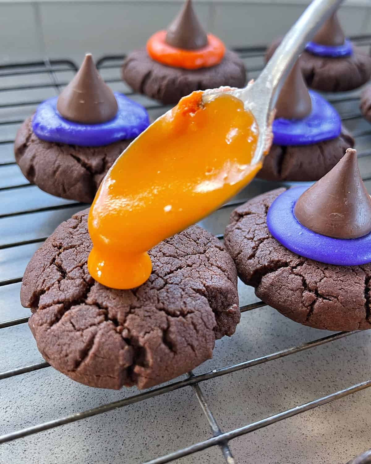 Orange icing being spooned on to a chocolate cookie