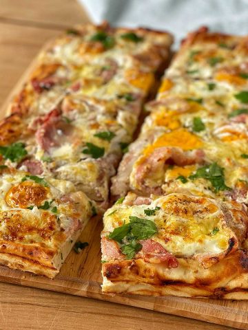 A large Breakfast Pizza Slab sitting on a wooden chopping board