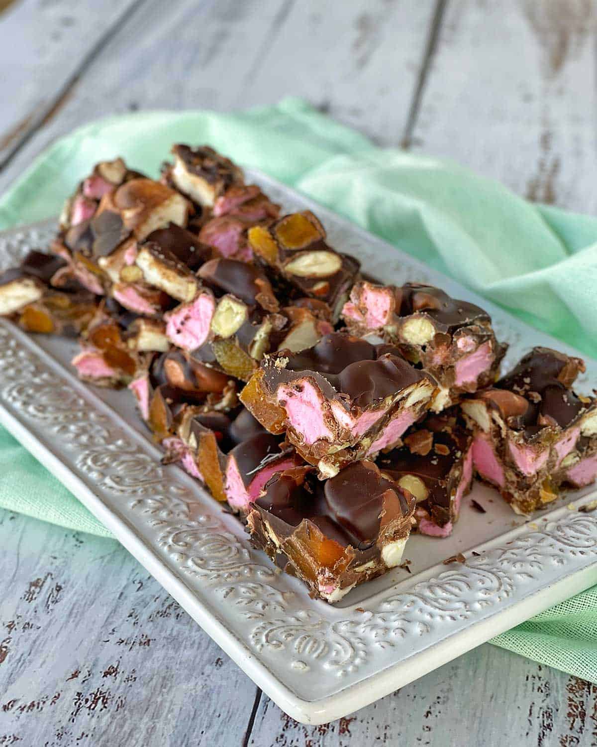 Pieces of Apricot Rocky Road sitting on a white platter with a green napkin underneath.
