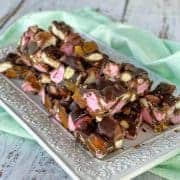 Pieces of apricot rocky road on a white platter, sitting on top of a mint green napkin.