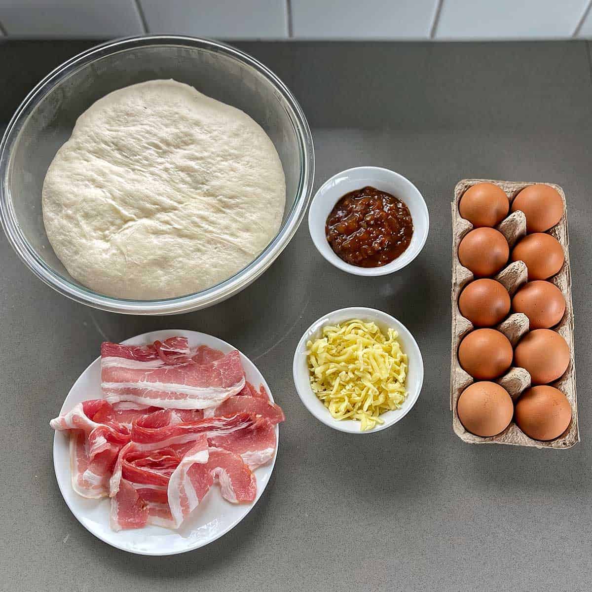 The ingredients for Breakfast Pizza Slab sitting on a grey bench.
