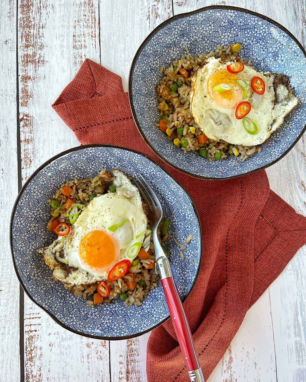 Two bowls of Mushroom Fried Rice on a wooden bench top.