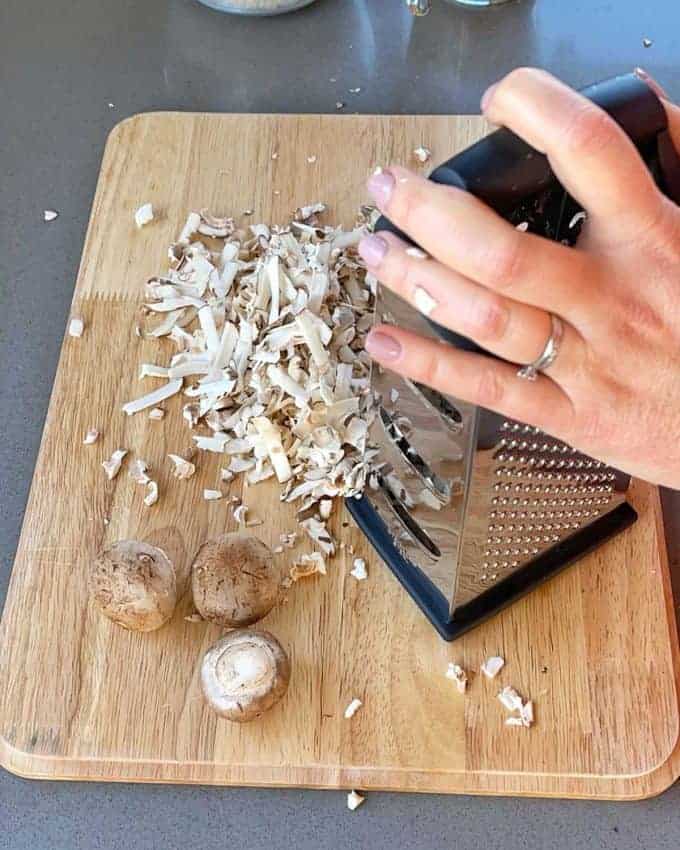 Mushroom Fried Rice Mushroom being grated on a wooden chopping board.
