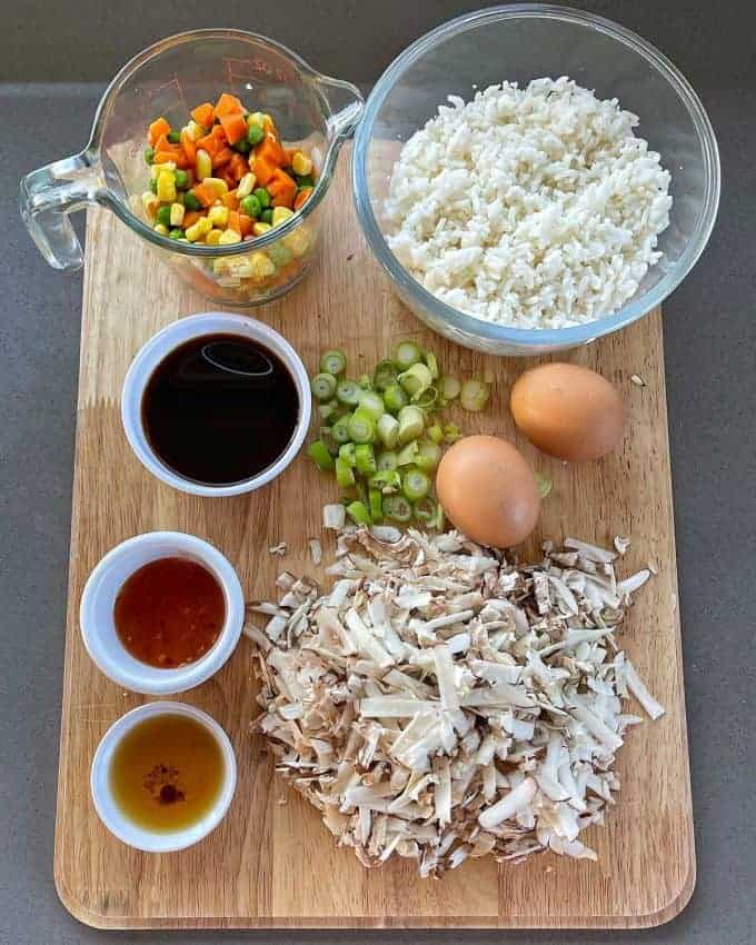 Mushroom Fried Rice The components for Mushroom Fried Rice on a wooden chopping board