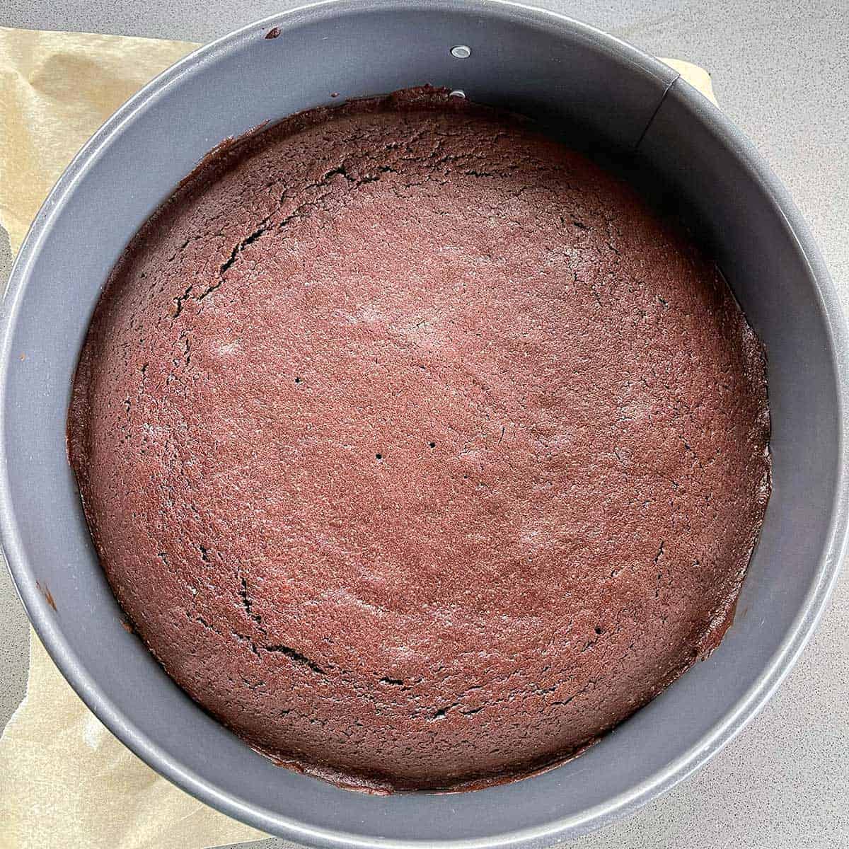 A cooked chocolate cake in a round cake tin.