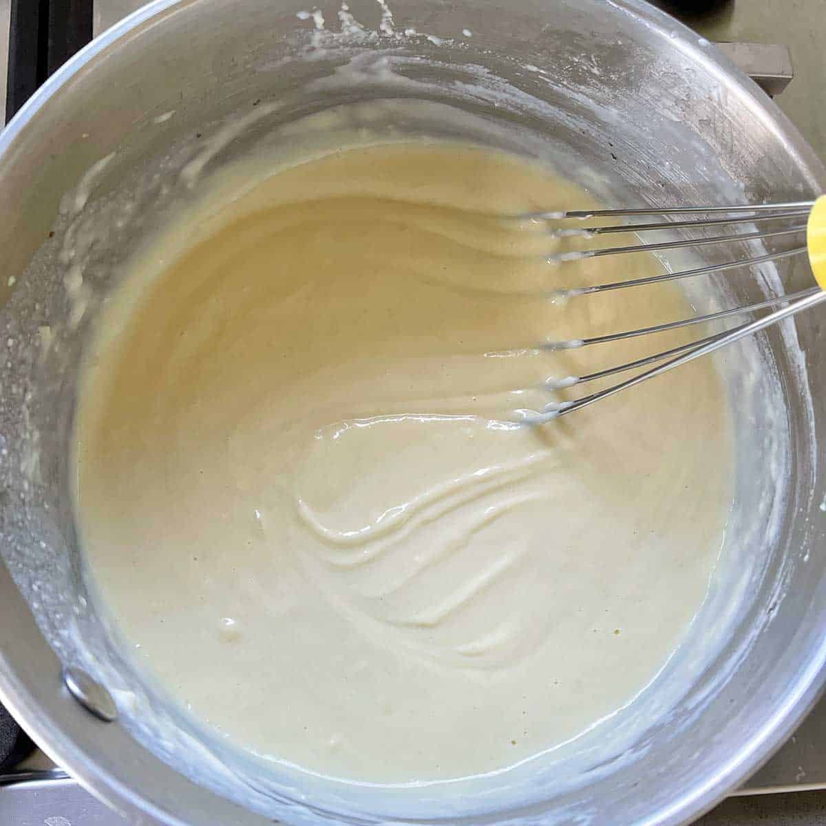 White sauce being stirred in a pot.