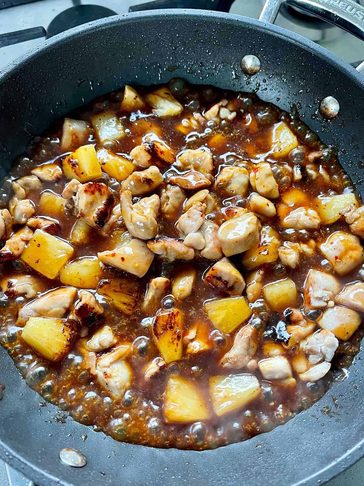 Pineapple and pork simmering in a pan