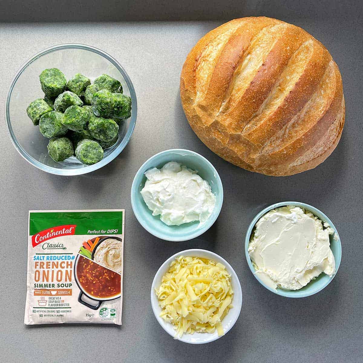 The ingredients for Creamy Spinach Cob Loaf on a grey bench