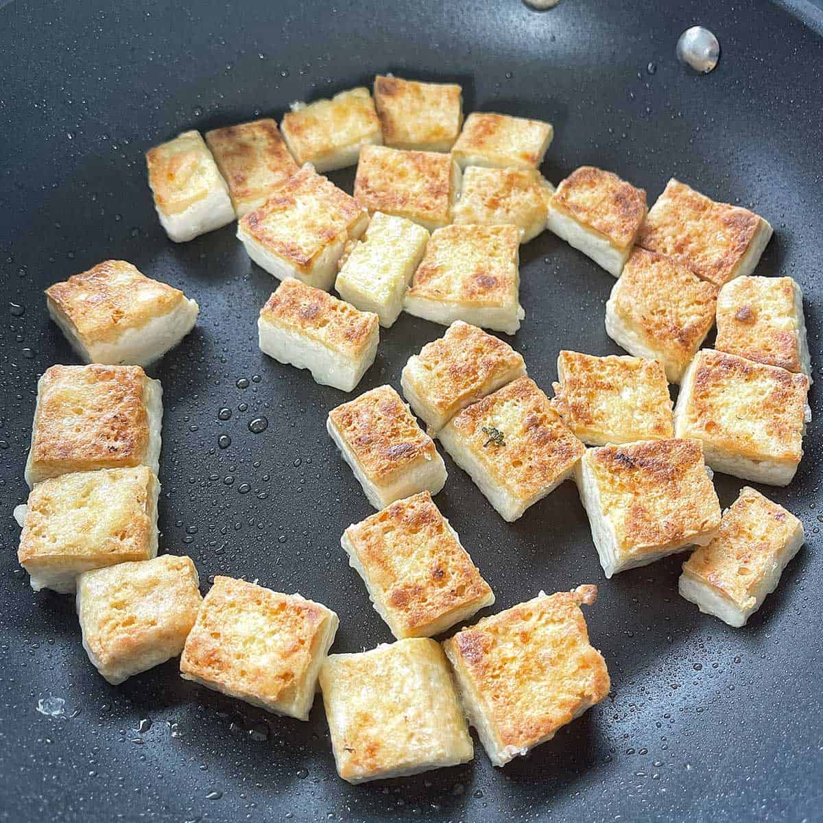 Tofu pan frying in a frying pan.