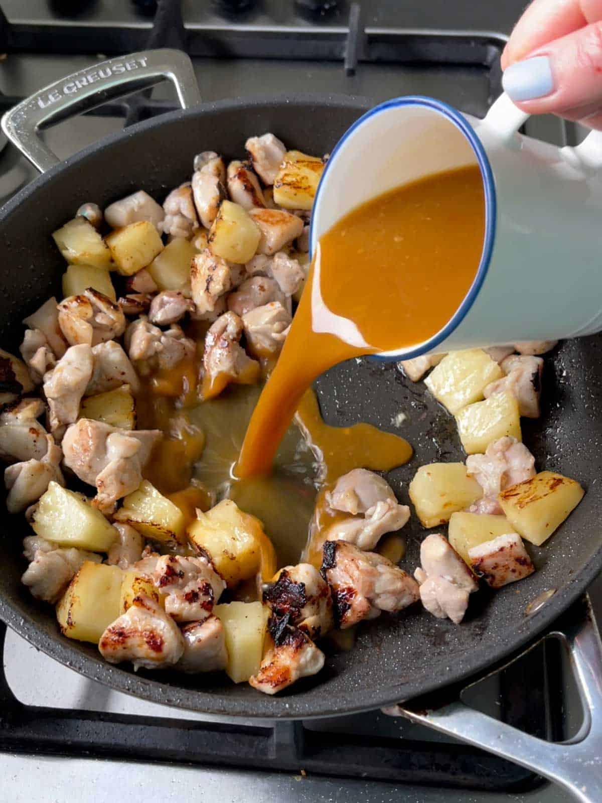 Pork and Pineapple cooking in a black frying pan.