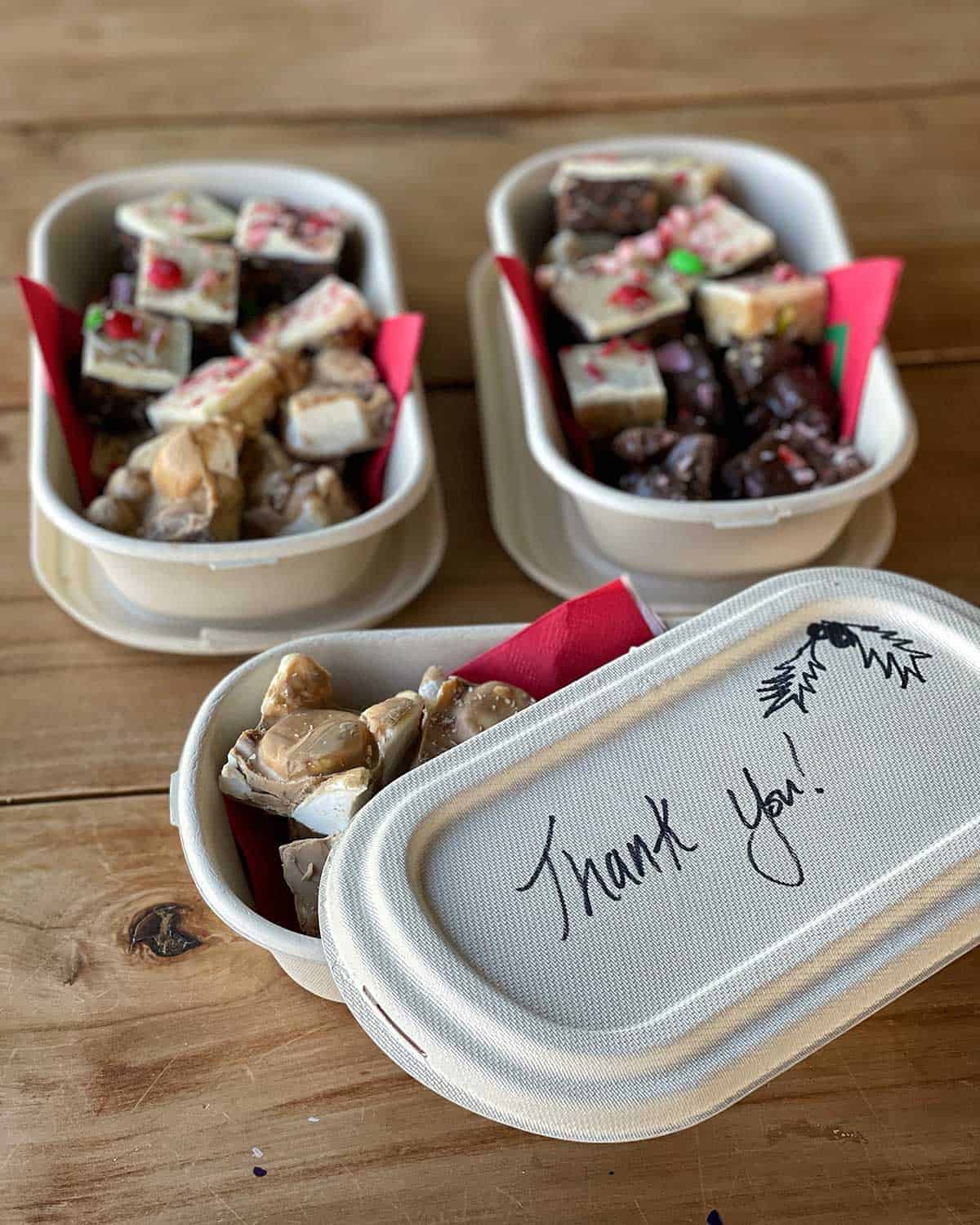 Christmas treats in three small containers sitting on a wooden bench