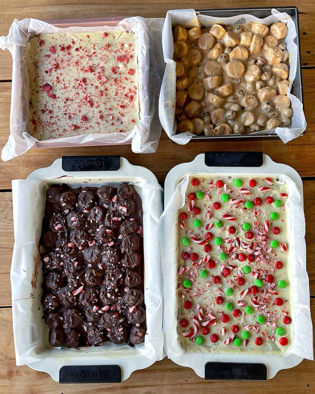 4 types of Christmas treats in baking trays sitting on a wooden bench