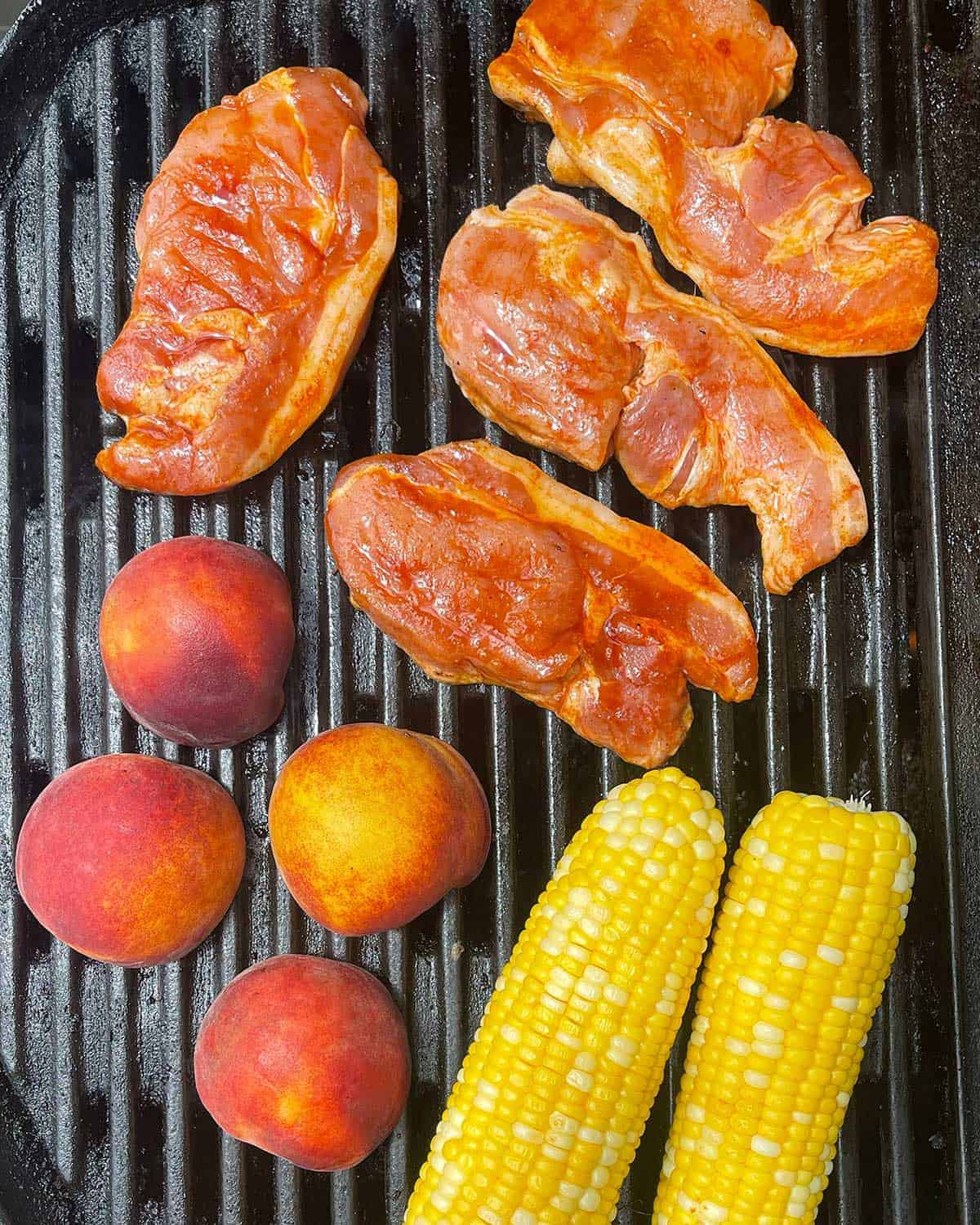  raw pork, peach and corn on a BBQ
