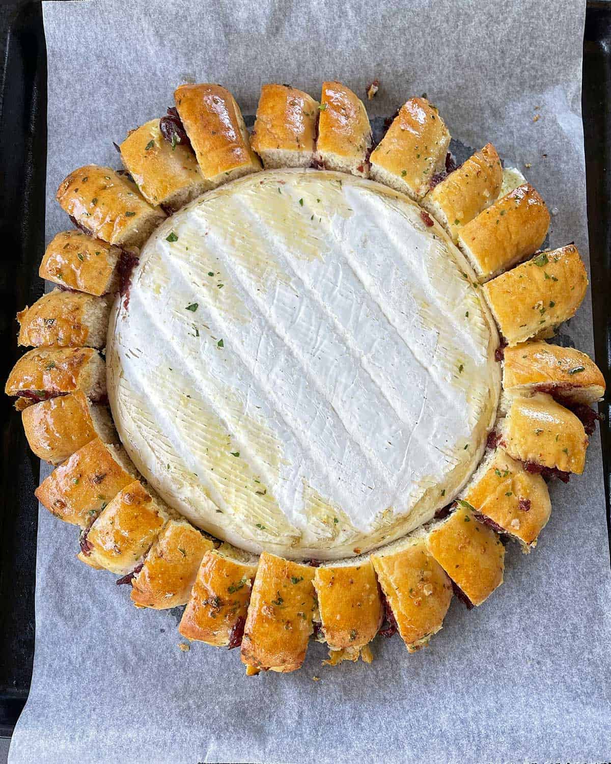 A cooked XL Brie Wreath on a lined baking tray.