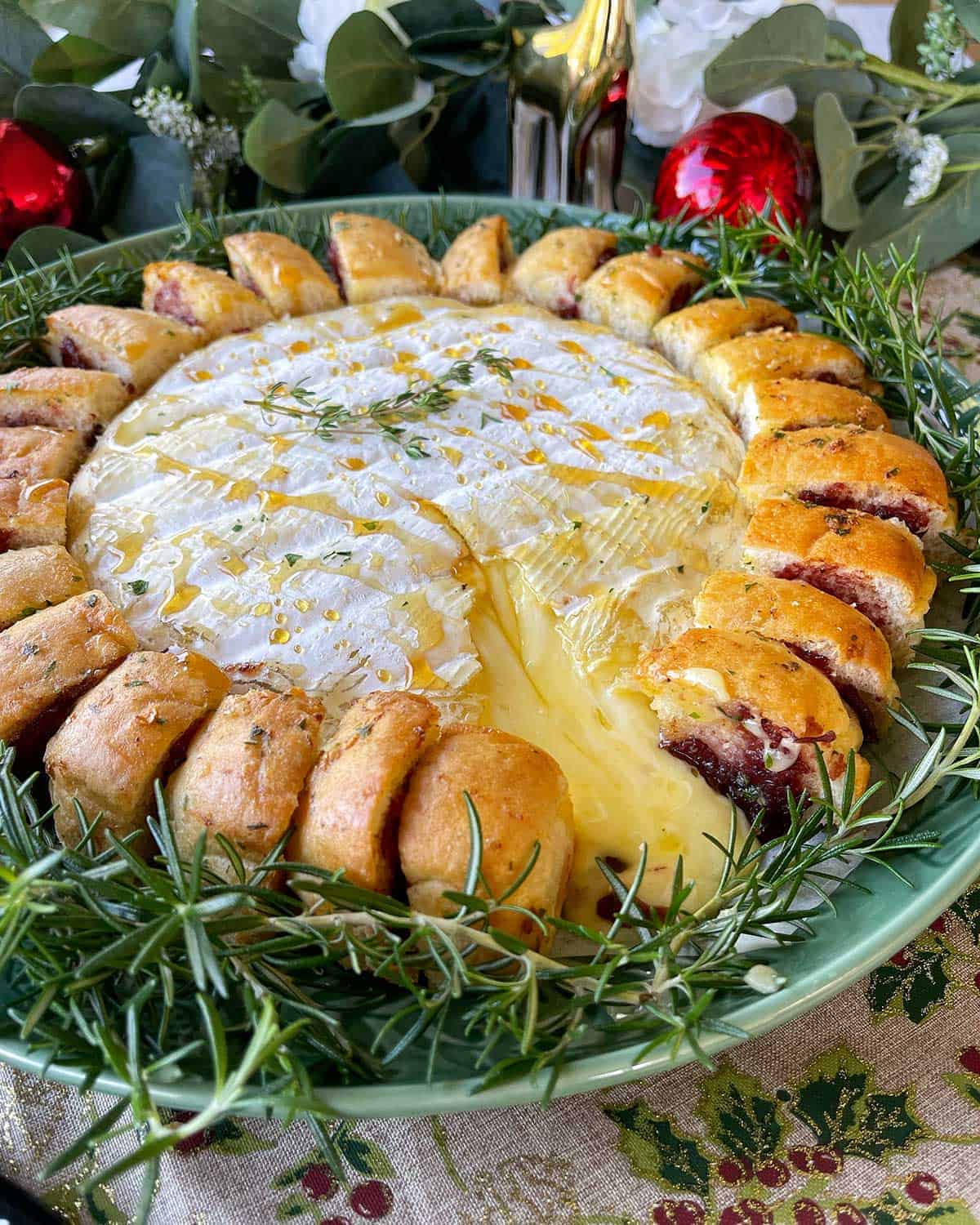 A close up of a large, cooked, brie surrounded by garlic bread on a green plate.