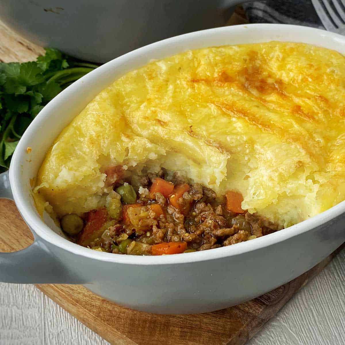 A close up of a beef cottage pie with a corner that has been served up already.